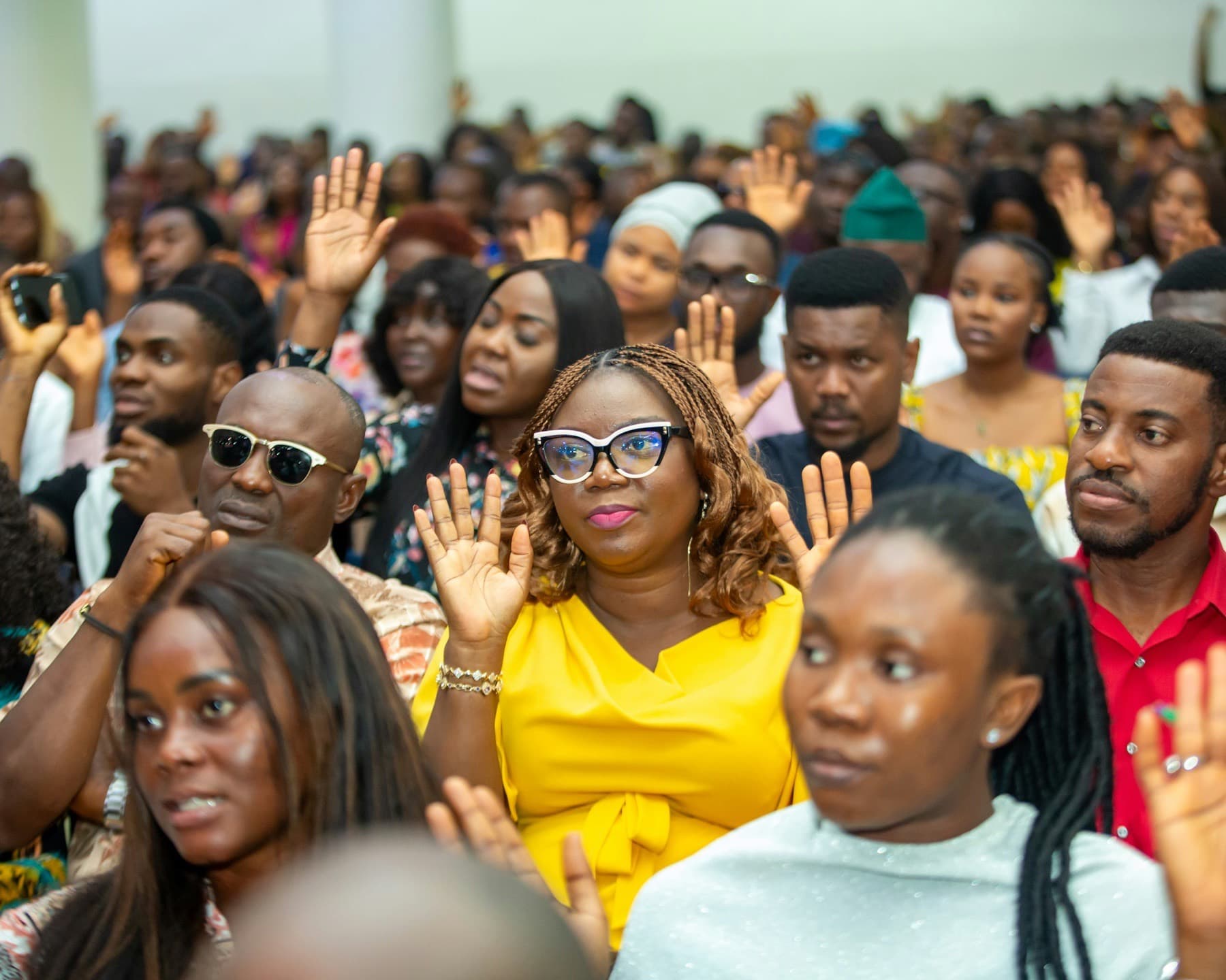 Engaged audience at a Nigerian event, several people raising their hands