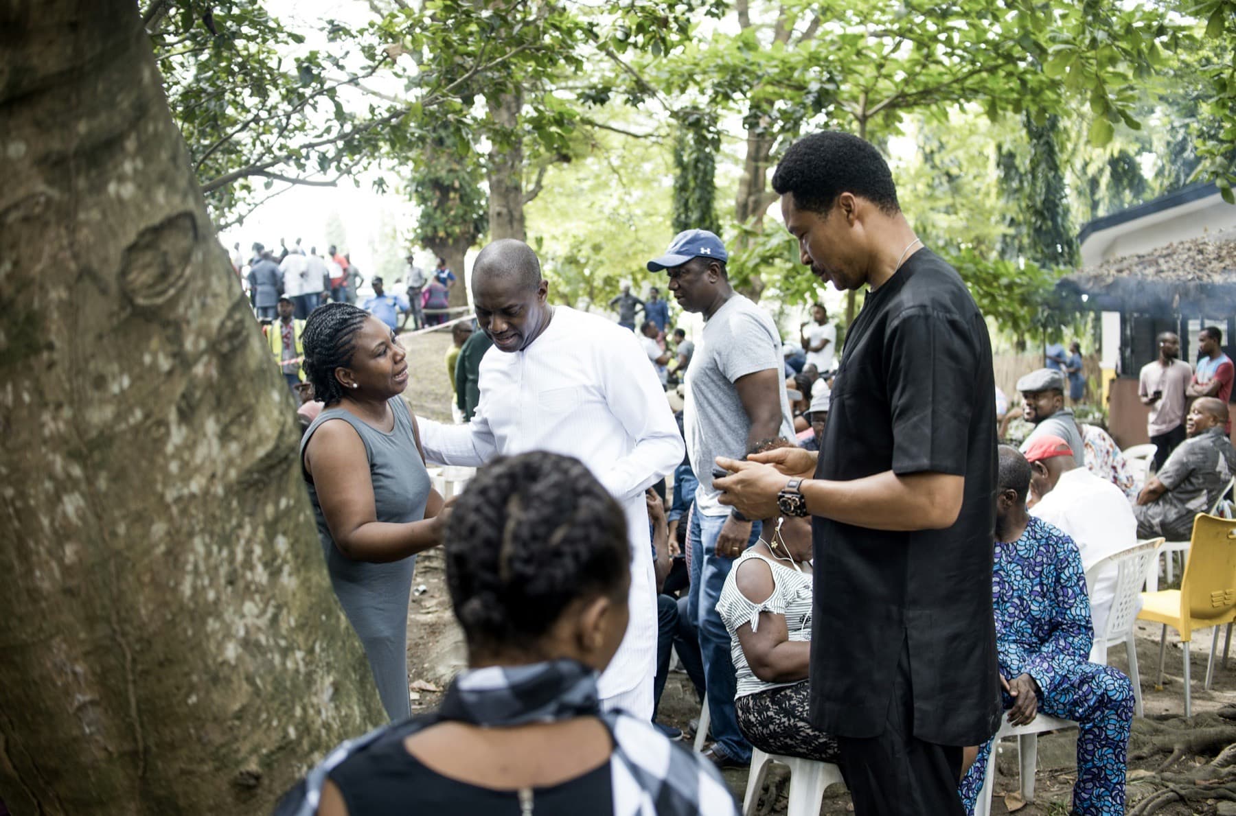 People gathering at an outdoor event under trees in Lagos