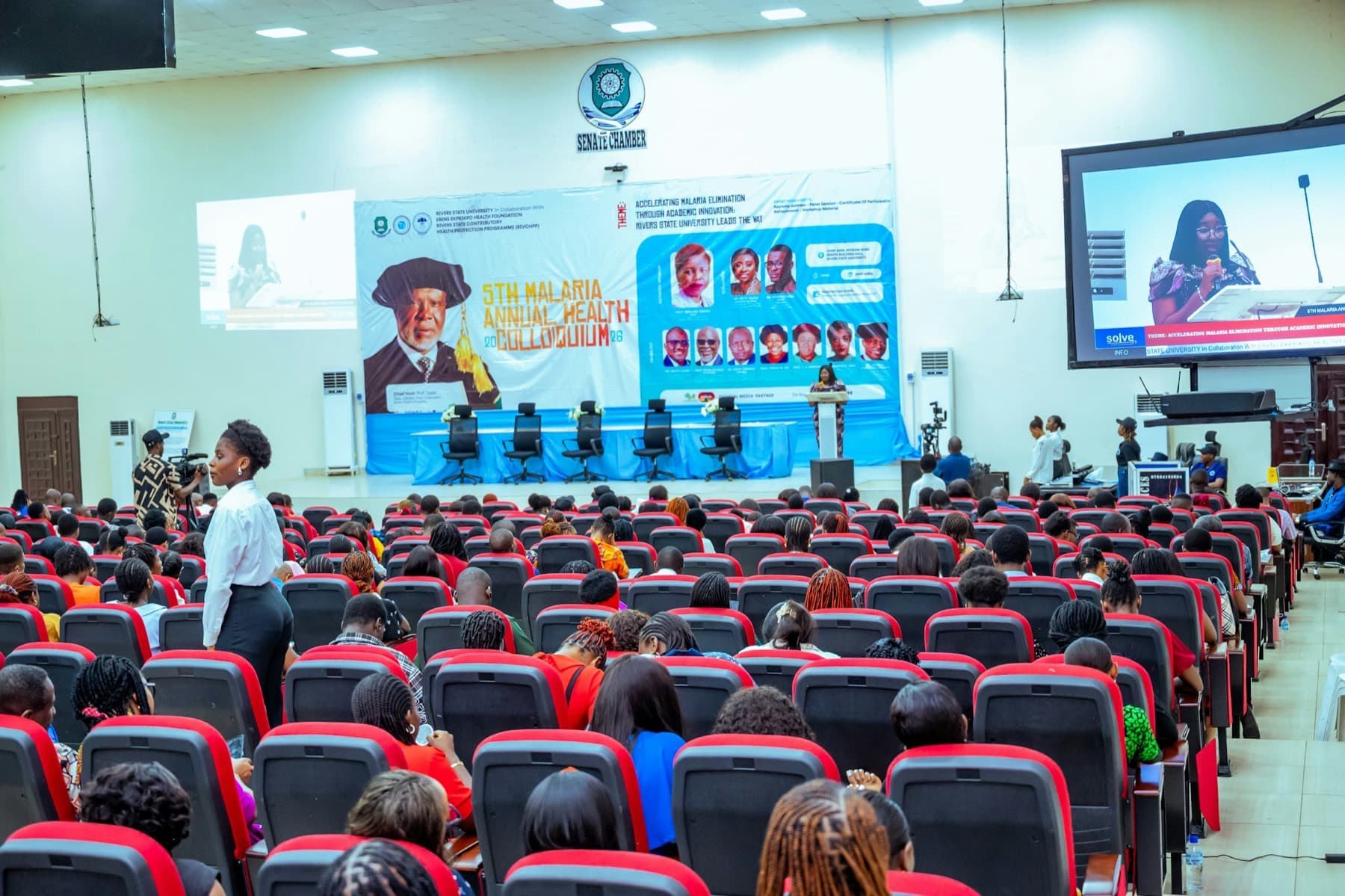 Large auditorium with an audience facing a stage and screens at a conference in Port Harcourt