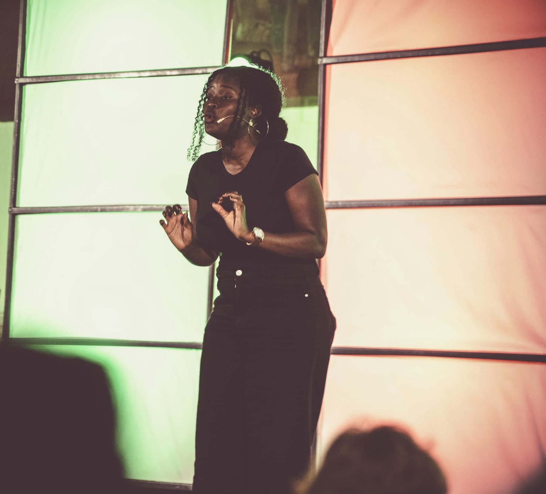 Woman speaking on stage in front of a colourful backdrop