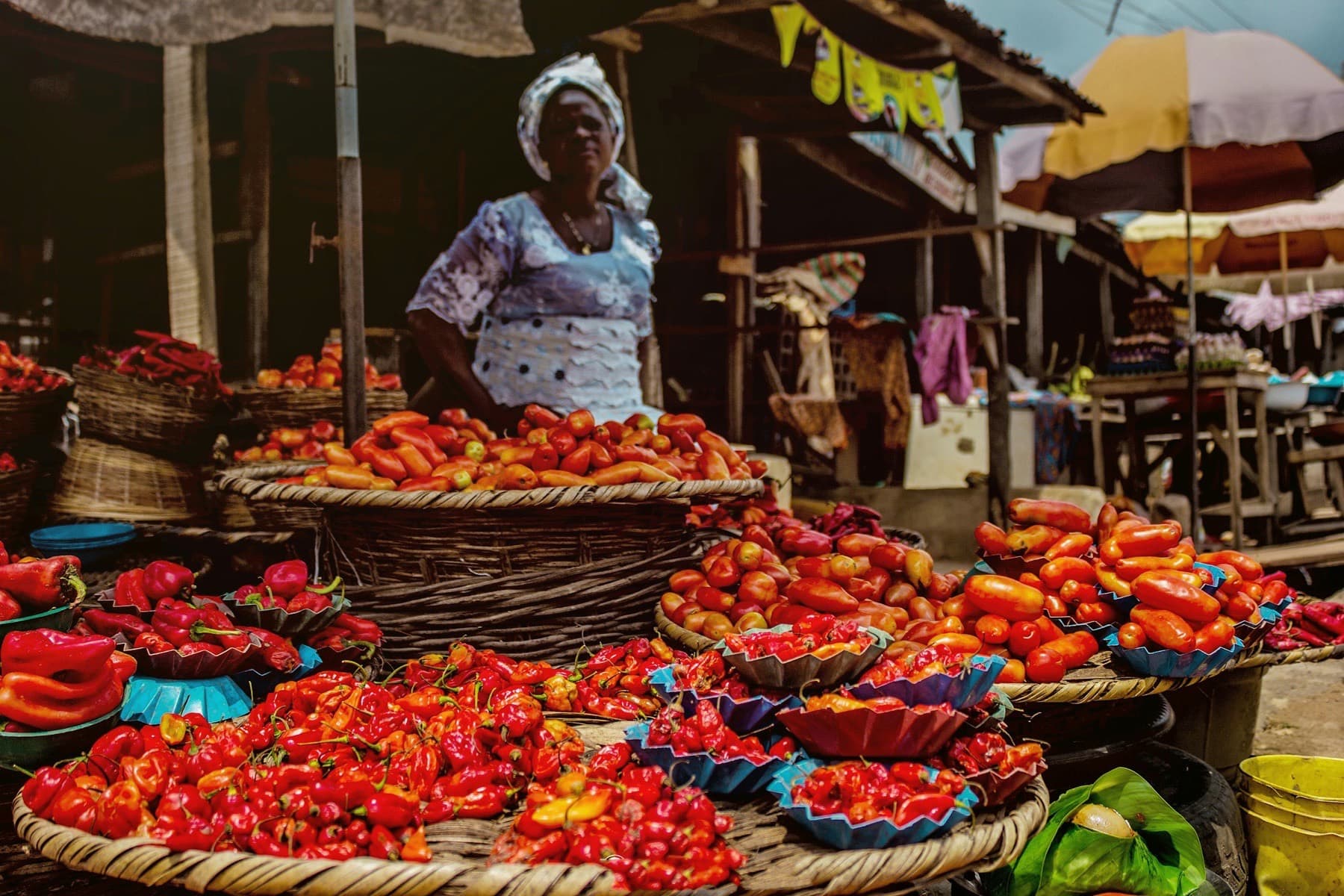 Market trader with baskets of red peppers and tomatoes in Nigeria