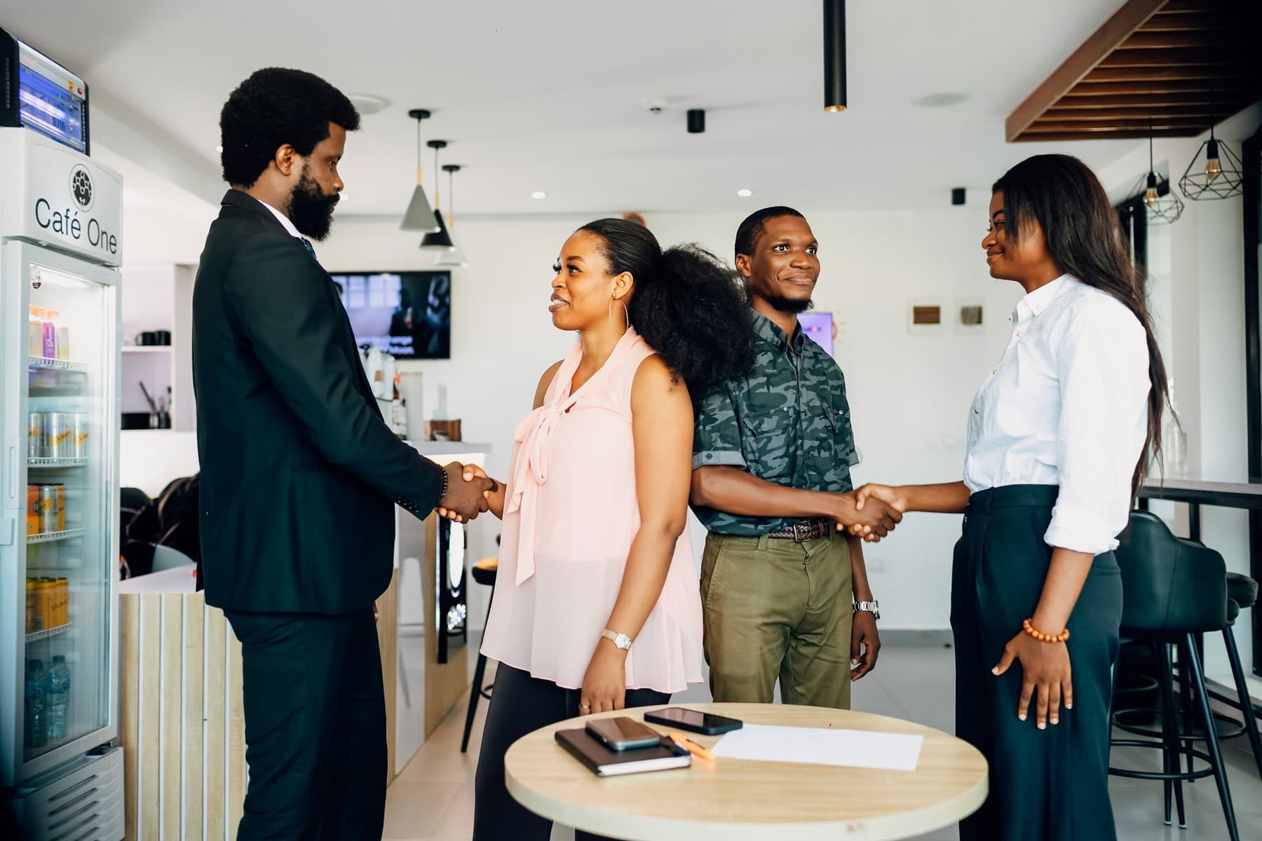 Four business people shaking hands around a table in a Lagos office