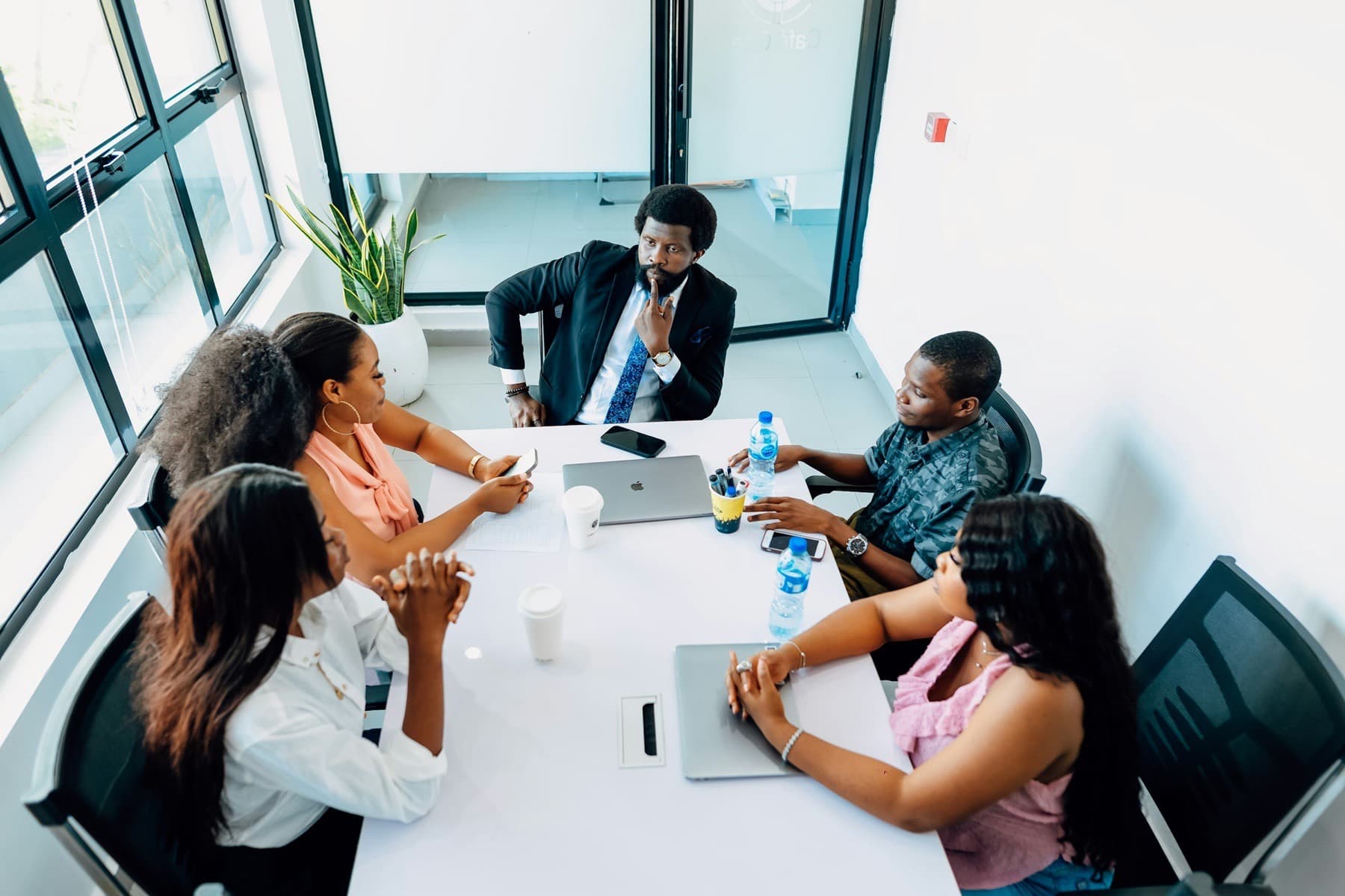 Team meeting around a white table in a glass-walled conference room in Lagos
