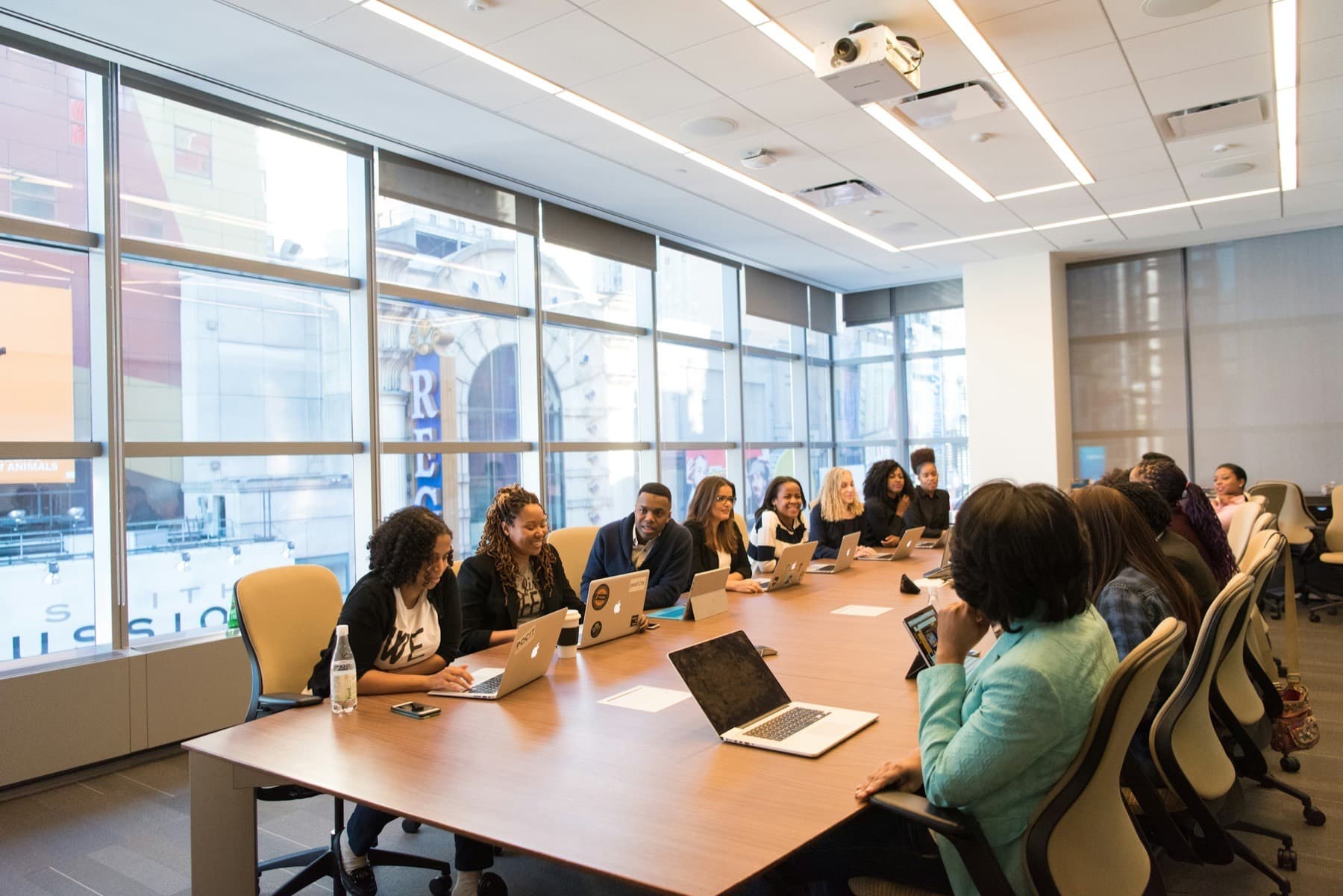Team of Black professionals seated around a long boardroom table with laptops